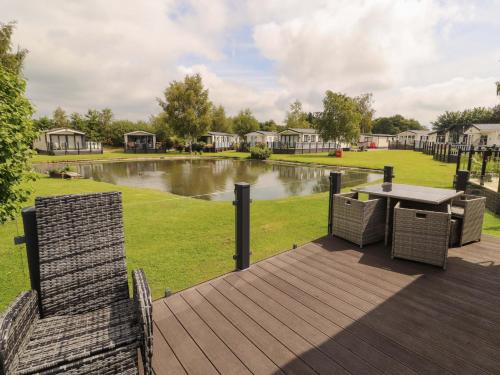 a deck with a table and chairs and a pond at 22 Yealand in Carnforth