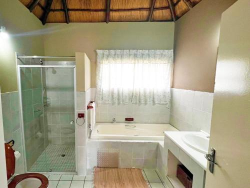 a bathroom with a tub and a shower and a sink at Protea Ridge Guest Cottages and Conference Centre in Roodepoort