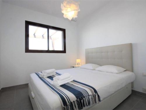 una camera da letto bianca con un letto e asciugamani di Apartamento encantador con piscina comunitaria en San Juan de los Terreros - ES-376-17 a Pulpí