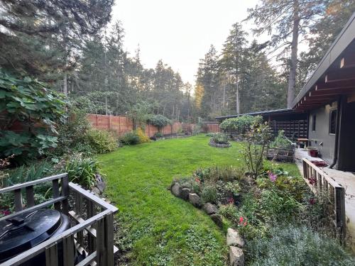 a yard with a fence and a garden with flowers at Cokely Cove Guesthouse - Oceanside Villa in Denman Island