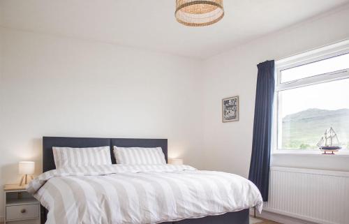 a white bedroom with a bed and a window at Creag Dubh in Camastianavaig