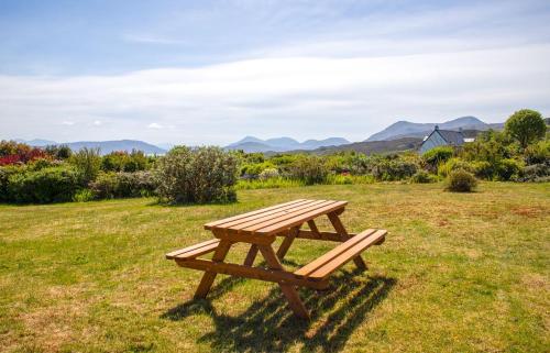 a wooden picnic table in a field with mountains in the background at Creag Dubh in Camastianavaig