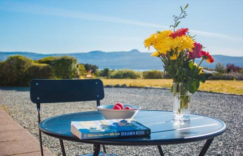 a glass table with a vase of flowers and a book at Creag Dubh in Camastianavaig