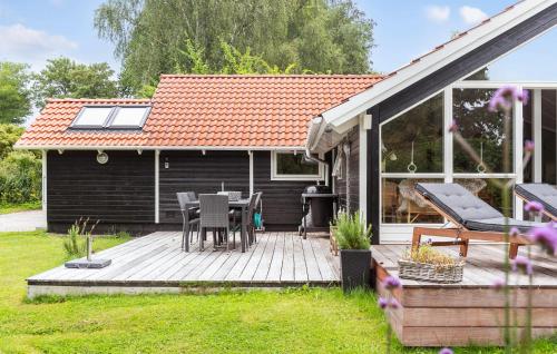 a wooden deck with a table and chairs in a yard at Stunning Home In Dronningmølle in Dronningmølle