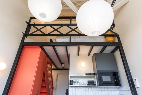 two white lanterns hang from the ceiling of a room at Maison Delage in Courbevoie