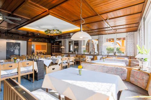 un ristorante con tavoli e sedie bianchi e soffitti in legno di Landgasthof Ritter a Orsingen-Nenzingen