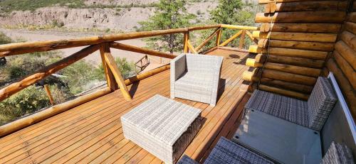 a deck with two chairs and a television on it at Cabin by the Mendoza River in Potrerillos