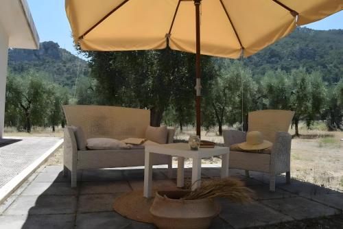 a patio with two chairs and a table with an umbrella at Meridiana case al mare in Mattinata