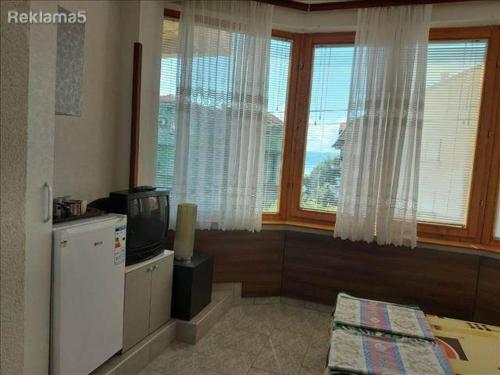 Una habitación con nevera, televisión y ventanas. en Amelia Accommodation Pestani Ohrid, en Ohrid