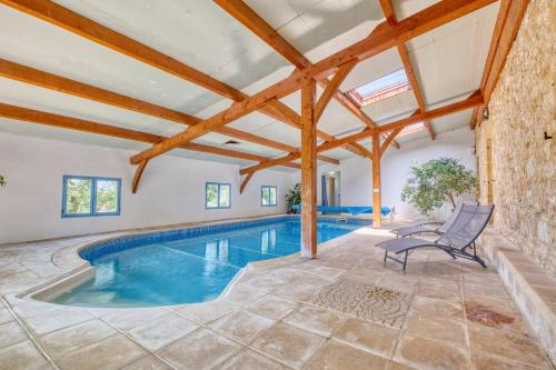 une piscine intérieure dans une maison avec poutres en bois dans l'établissement La Roulotte Jaune, à Monsac