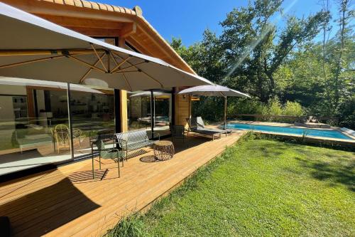 a wooden deck with an umbrella and a swimming pool at La Maison Boisée - Welkeys in Orx