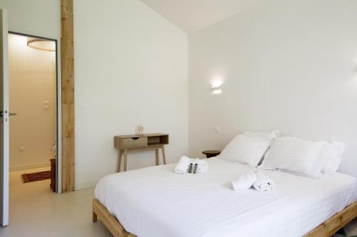 a bedroom with a large white bed with towels on it at La Maison Boisée - Welkeys in Orx