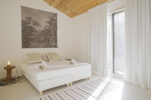 a white room with a bed and a large window at La Maison Boisée - Welkeys in Orx