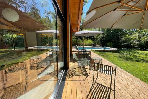 a deck with chairs and an umbrella and a pool at La Maison Boisée - Welkeys in Orx