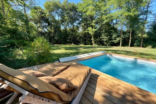 a swimming pool with a lounging bed next to at La Maison Boisée - Welkeys in Orx