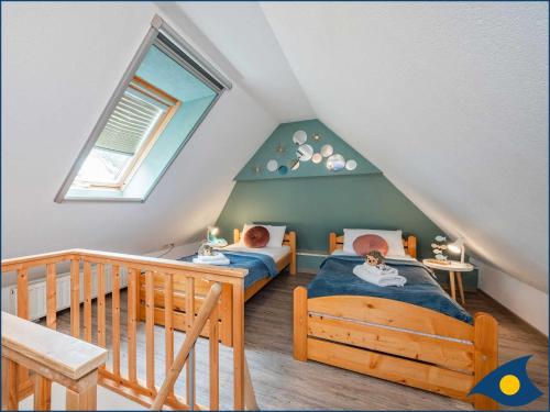 a attic room with two beds and a window at Fraeulein Loddin Whg_ Hugo in Kolpinsee