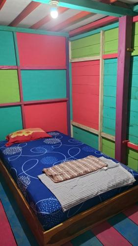 Pulau SarangにあるSurf House Hostelのカラフルなドア付きのベッドルーム1室、ベッド1台が備わる客室です。