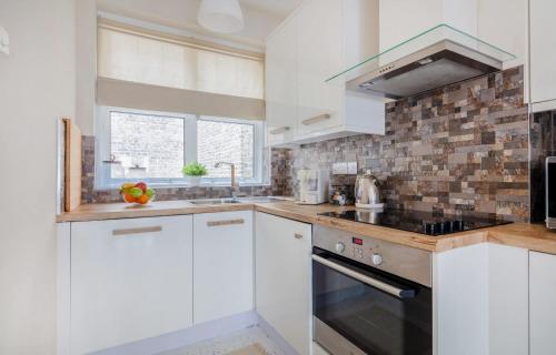 a kitchen with white cabinets and a stove top oven at BnBNova - 1BR - Holborn & Central London - The Museum in London