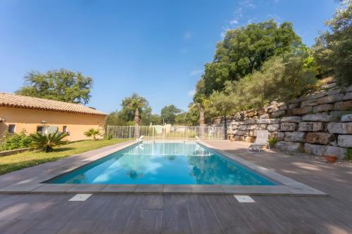 a swimming pool in a yard with a stone wall at Maison d'hôtes Collobrières in Collobrières