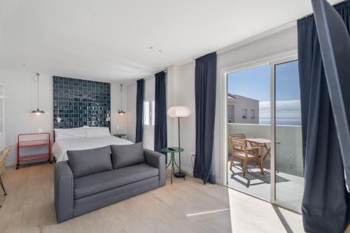 a bedroom with a bed and a couch and a balcony at Nomad Hub Tenerife in Barranco Grande