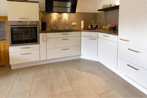 a kitchen with white cabinets and a tile floor at Sophie -203- in Mittenwald