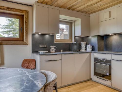 une cuisine avec des armoires blanches et une table dans l'établissement Appartement cosy 2 pièces à Megève, proche pistes et golf, avec balcon et jardin, pour 4 personnes. - FR-1-453-83, à Megève