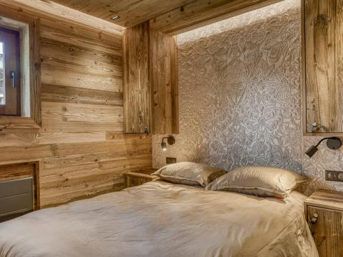 - une chambre dotée de murs en bois et d'un lit avec deux oreillers dans l'établissement Appartement cosy 2 pièces à Megève, proche pistes et golf, avec balcon et jardin, pour 4 personnes. - FR-1-453-83, à Megève