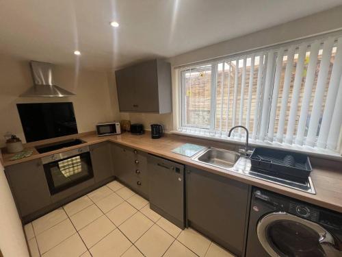a kitchen with a sink and a dishwasher at Blyton 2-Bed Cottage Parking 30m to Lincoln in Blyton