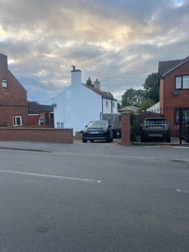 a street with cars parked in front of a white building at Blyton 2-Bed Cottage Parking 30m to Lincoln in Blyton