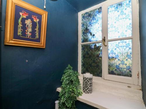 una parete blu con una finestra e una pianta sul davanzale di The Little Laura Ashley House a Machynlleth