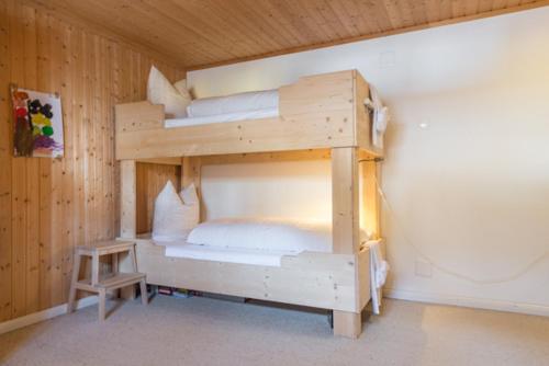 two bunk beds in a wooden room with a table at Edelweiss Ferienwohnung, Casa Dadens, Flims Dorf , 6027 in Flims