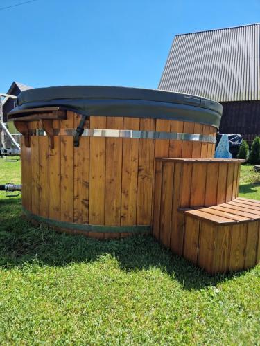 a wooden tub with a bench in the grass at Babiogórskie Domki in Lipnica Wielka