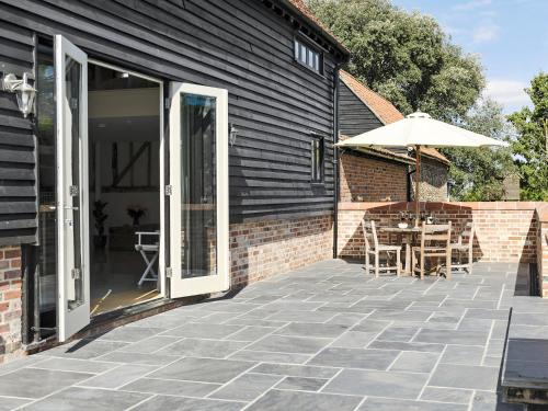a patio with a table and an umbrella at Tatters Barn in Bradwell