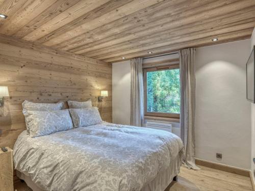 une chambre avec un lit et un mur en bois dans l'établissement Charmant T3 rénové avec terrasse à 800m du centre de Megève, parking et wifi inclus - FR-1-453-166, à Megève
