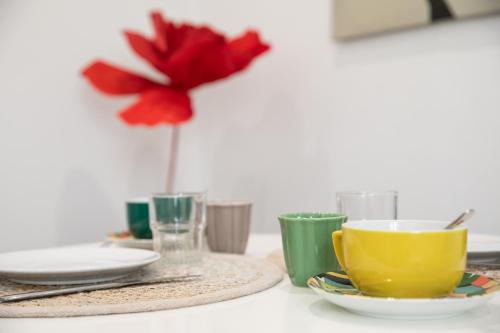 a table with plates and cups and a red flower at AUDREY-Quartier Mairie-arènes antiques-Clim in Périgueux