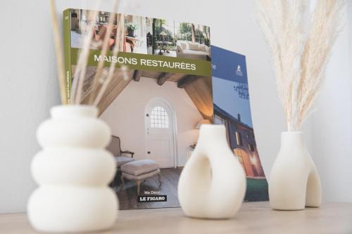 three white vases sitting on a table next to a magazine at AUDREY-Quartier Mairie-arènes antiques-Clim in Périgueux