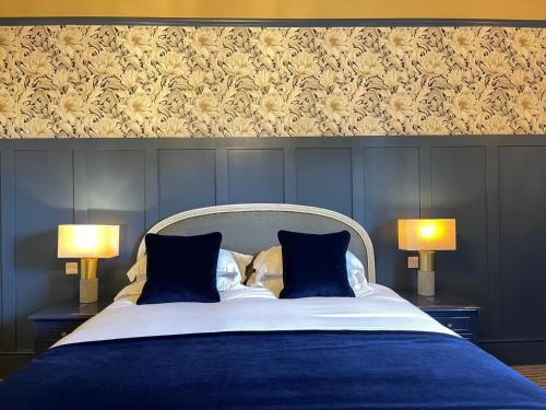 una camera con un letto blu con due lampade di The King's Head a Winchester