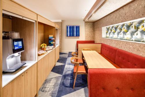 a restaurant with a table and chairs and a television at Crowne Plaza Manchester Airport by IHG in Hale