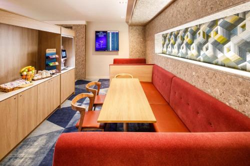 a restaurant with a wooden table and red chairs at Crowne Plaza Manchester Airport by IHG in Hale
