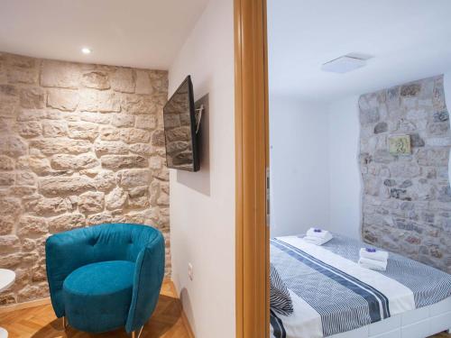 a bedroom with a bed and a blue chair at Apartment Heart of Trogir in Trogir