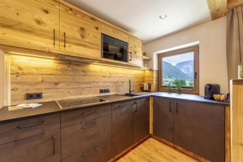 a kitchen with wooden walls and a sink and a window at Mühlanderhof Apt Piz Lad in Resia
