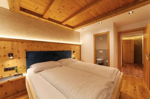 a bedroom with a large bed with a wooden wall at Mühlanderhof Apt Piz Lad in Resia