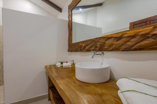a bathroom with a white sink and a mirror at Akua Suites Ocean View in Tarcoles