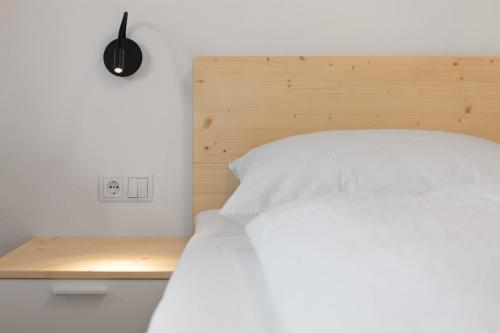 a bedroom with a white bed with a wooden headboard at Unterdornerhof Algund in Lagundo