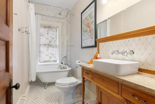 a bathroom with a sink and a tub and a toilet at Historic Queen Anne Family Home w Modern Comforts in Harpers Ferry