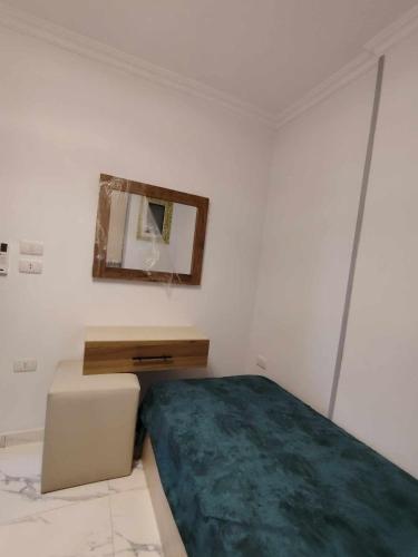 a white bedroom with a bed and a mirror at بورتو جولف in El Alamein
