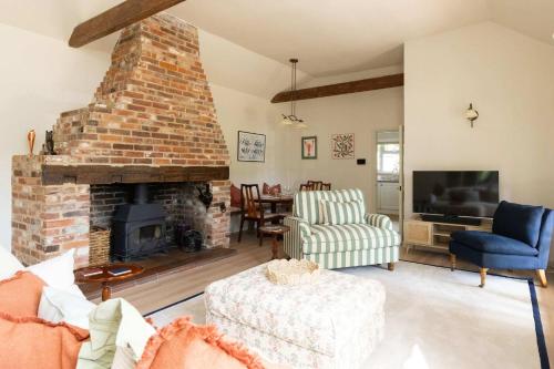 a living room with a brick fireplace and a tv at Homely Cottage for 6 Near Chichester & Goodwood in Chichester