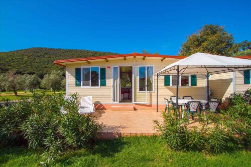 a small yellow house with a table and an umbrella at Mobilehome in Rabac 16897 in Rabac