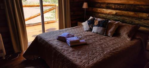 a bed in a log cabin with two boxes on it at Cabin by the Mendoza River in Potrerillos