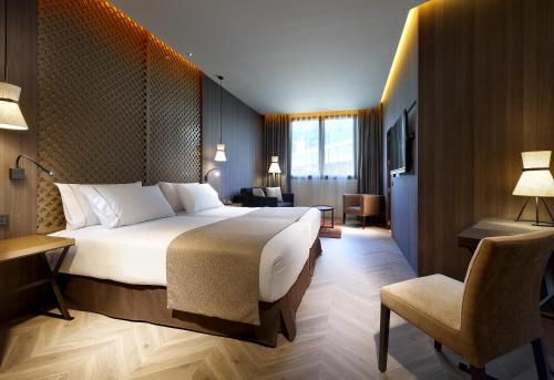 グラナダにあるÁurea Washington Irving by Eurostars Hotel Companyの大きなベッドと椅子のあるホテルの部屋